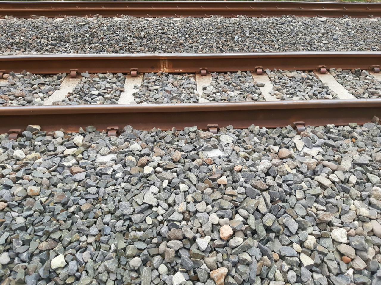 A rail is two equal length metal rods mounted on a bearing as the base of a railroad runway. Ballast stone on the rail to dampen the vibration and bending of the rail due to the weight of the train.